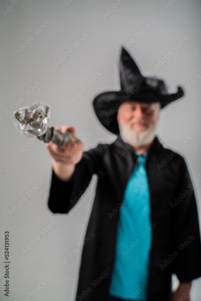 out of focus old wizard man  shows magic wand in a Halloween costume, on a white background