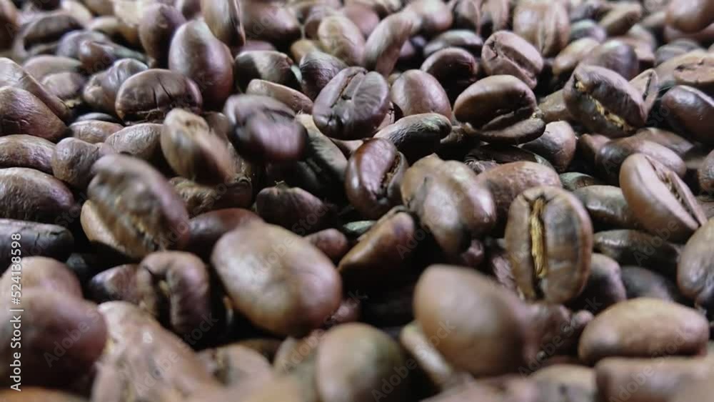 Super close-up of roasted coffee beans falling on coffee texture in slow motion Super close-up of roasted coffee beans falling on coffee texture in slow motion