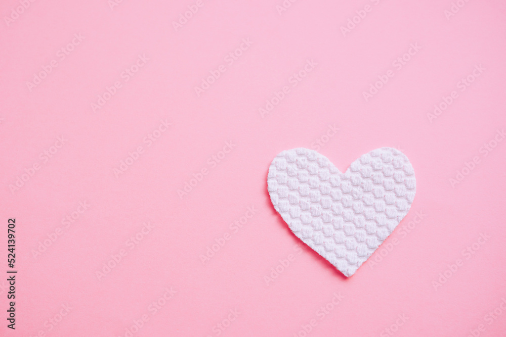 White fabric heart on pale pink table