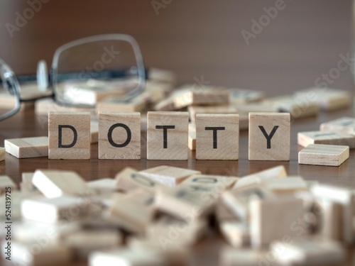 dotty word or concept represented by wooden letter tiles on a wooden table with glasses and a book photo