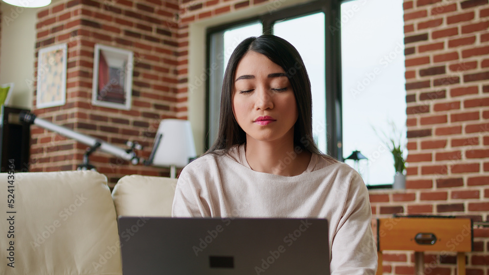 Focused freelancer woman working remotely from home on modern laptop. Beautiful young adult person doing remote freelancing work on portable computer while sitting on sofa inside apartment. Focused freelancer woman working remotely from home on modern laptop. Beautiful young adult person doing remote freelancing work on portable computer while sitting on sofa inside apartment.