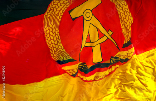 Ein Stück der Fahne der ehemaligen DDR mit Emblem, Hammer, Zirkel, Ährenkranz.