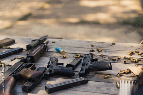 Rifle and guns stored on wooden table with bullets ammunition clips and shells. Military equipment. Firing range. Horizontal shot. High quality photo
