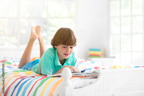 Child reading in bed. Kids read. Boy at home.