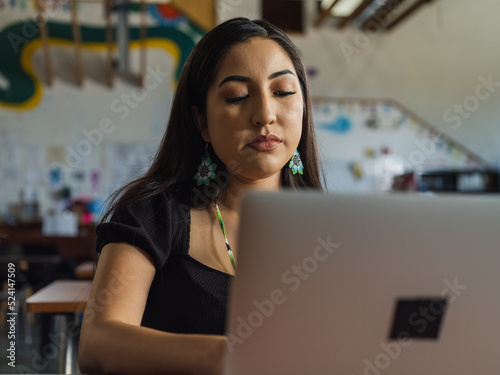 Εκτύπωση καμβά Close up of a native girl with beaded earrings typing on her laptop in the class