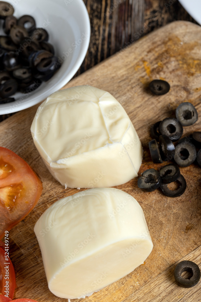 Fresh cow's milk cheese is cut on a board