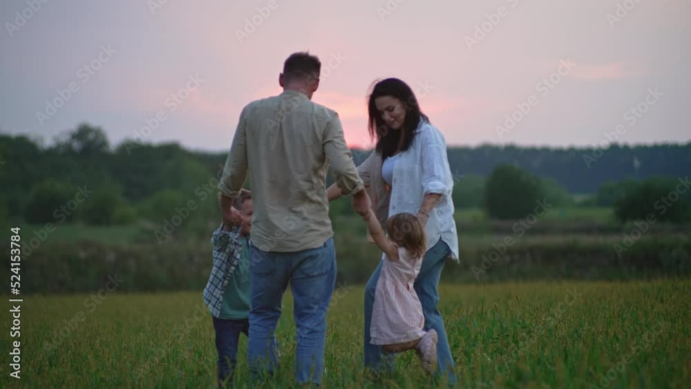 Family holding hands dancing at sunset in nature. Happy parents and children rejoice and have fun together. High quality 4k footage Family holding hands dancing at sunset in nature. Happy parents and children rejoice and have fun together. High quality 4k footage
