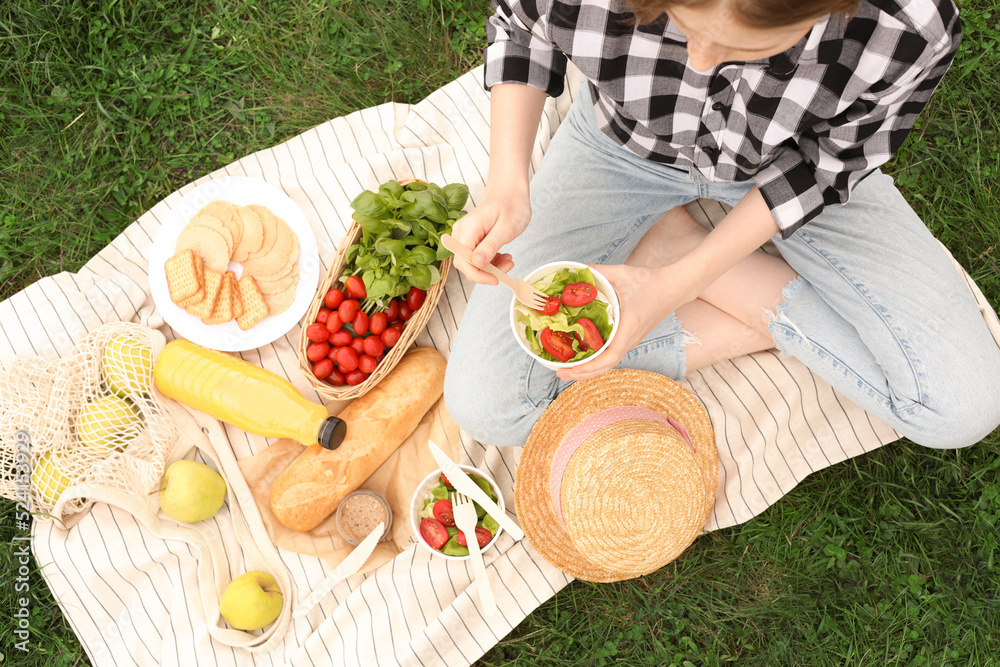 Girl having picnic on green grass in park, above view Girl having picnic on green grass in park, above view