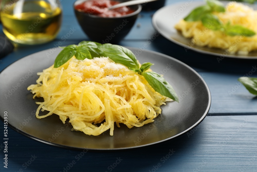 Tasty spaghetti squash with basil and cheese served on blue wooden table, closeup Tasty spaghetti squash with basil and cheese served on blue wooden table, closeup