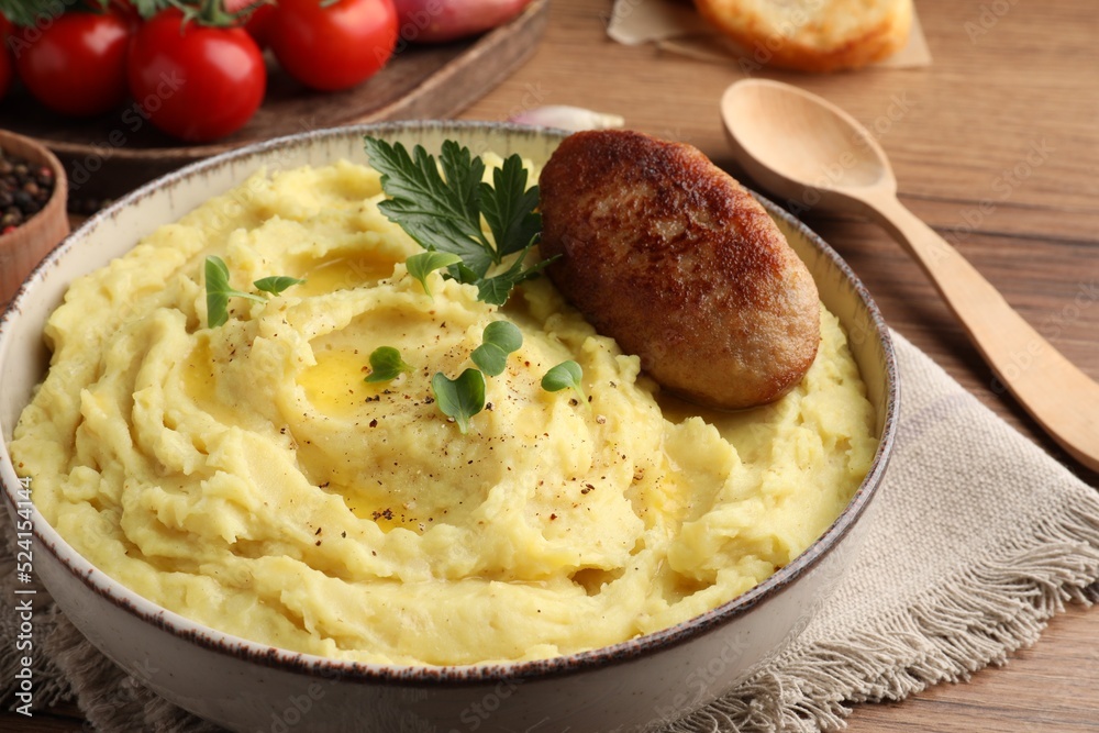 Bowl of tasty mashed potatoes with parsley, black pepper and cutlet served on wooden table, closeup Bowl of tasty mashed potatoes with parsley, black pepper and cutlet served on wooden table, closeup