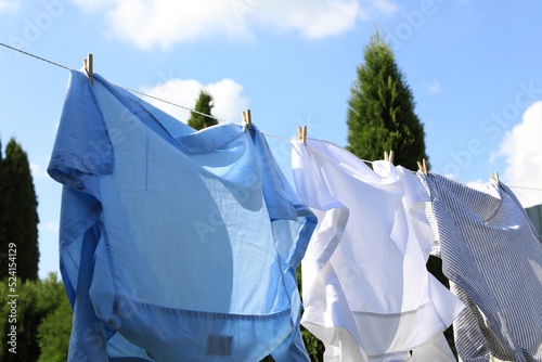 Clean clothes hanging on washing line in garden, closeup. Drying laundry