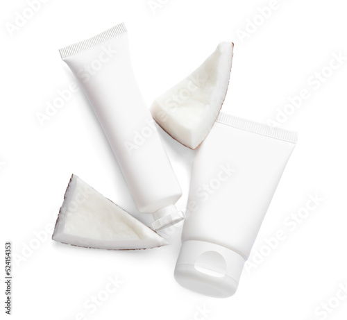 Tubes of hand cream and coconut pieces on white background, top view