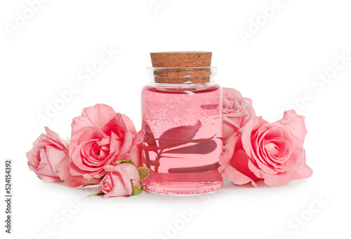 Bottle of essential rose oil and flowers on white background photo