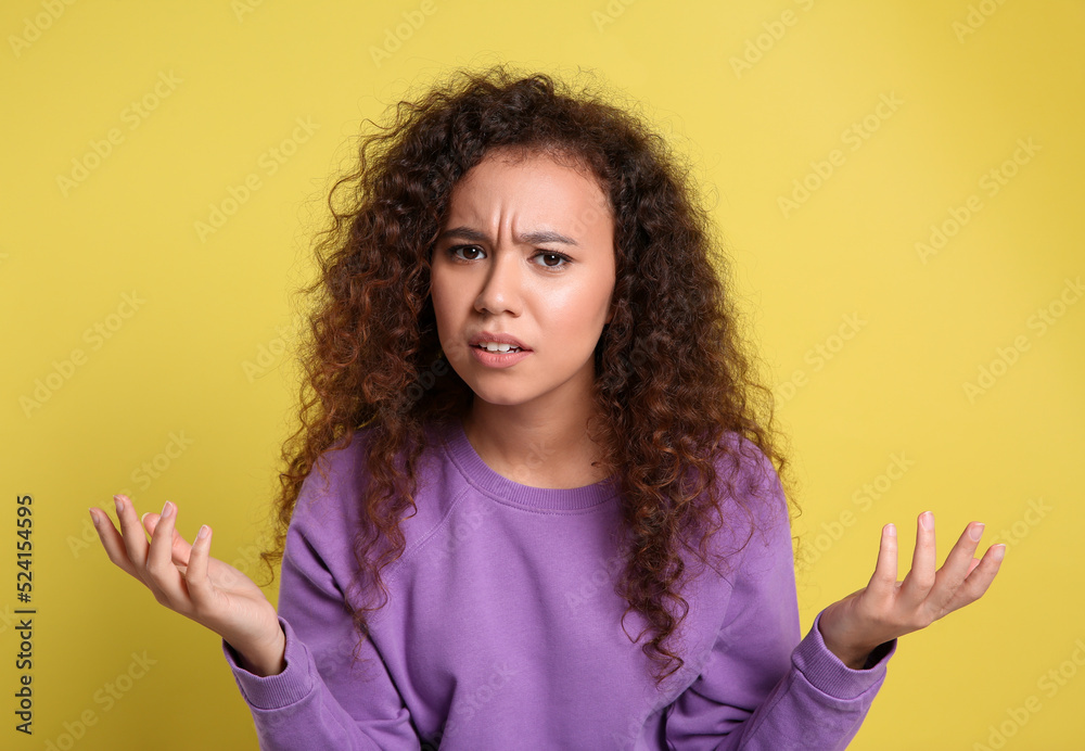 Confused African-American woman on yellow background. Thinking about difficult question Confused African-American woman on yellow background. Thinking about difficult question