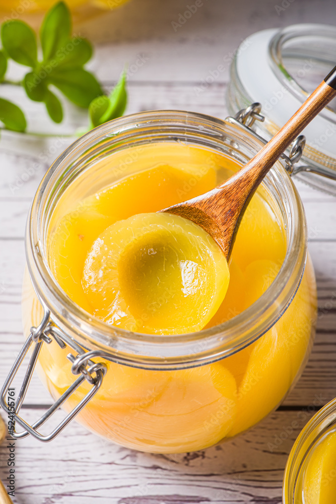 sweet canned yellow peach with spoon in glass jar on table sweet canned yellow peach with spoon in glass jar on table