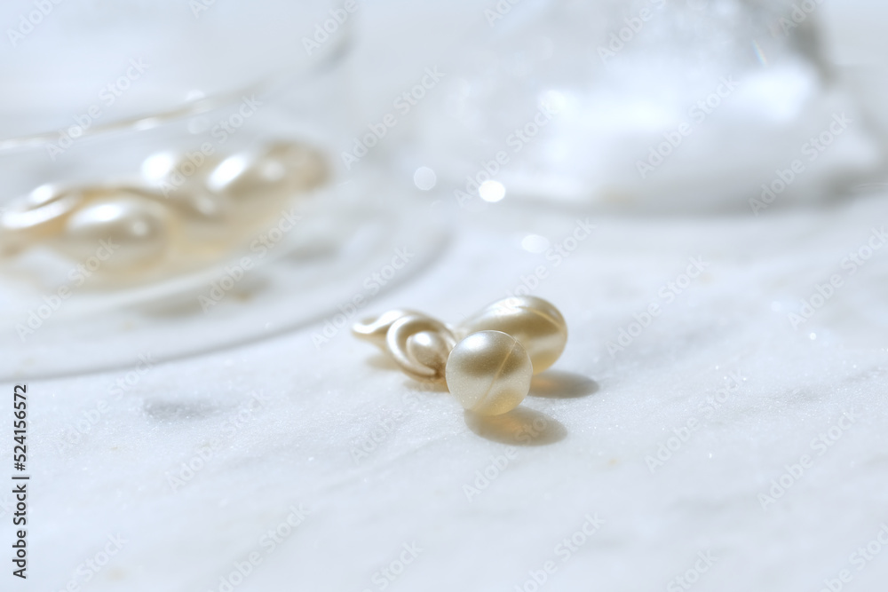 Serum capsules in petri dish for healthy skin with ice balls. Orange semitransparent capsules. Anti-wrinkle rejuvenation skin treatment. Beauty product presentation. Off white stone marble background. Serum capsules in petri dish for healthy skin with ice balls. Orange semitransparent capsules. Anti-wrinkle rejuvenation skin treatment. Beauty product presentation. Off white stone marble background.