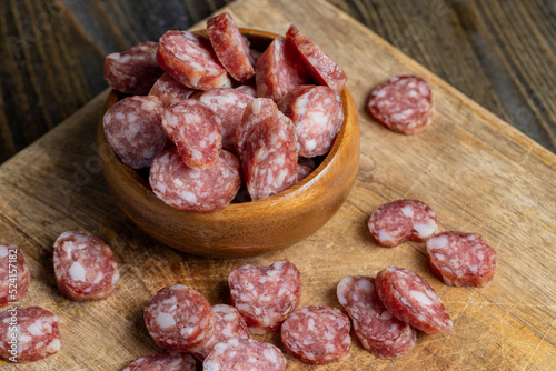 sliced thin sausage with bacon on a wooden dish