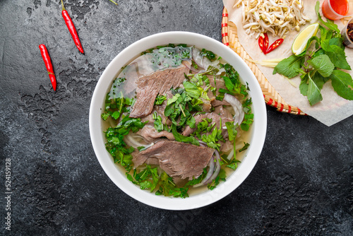 Soup Pho Bo with beef and noodles top view on dark stone table