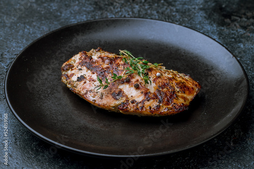 Grilled chicken Breasts on black plate on dark stone table macro close up