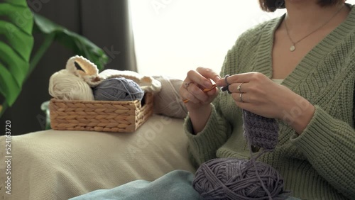 Faceless. Hands of young pretty woman holding crochet hook , enjoy knitting , sit on sofa. Girl knits handmade scarf at home. Hobby knitting and needlework for mental health. 4k footage