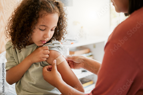 Covid nurse vaccinating child putting a bandage on at a clinic. Doctor applying plaster on girl after an injection at health centre. Pediatric, immunity and prevention at medical childrens hospital photo