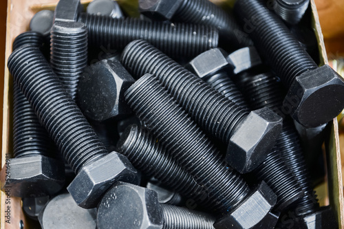 Pile of hardened blued metal bolts for fastening in crate