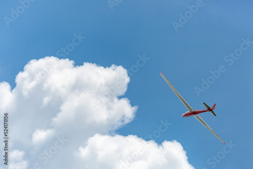 青空と白い雲を背景に飛行するグライダー。レジャー,趣味,エコロジーのイメージ