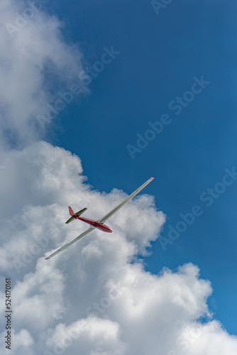 青空と白い雲を背景に飛行するグライダー。レジャー,趣味,エコロジーのイメージ