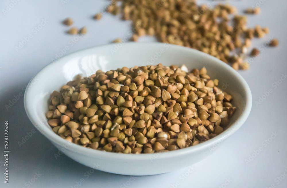 Raw Buckwheat in white ceramic bowl on wooden wood Raw Buckwheat in white ceramic bowl on wooden wood