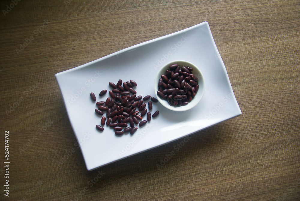 Organic kidney beans in white plate on wooden table.The kidney bean is a variety of the common bean (Phaseolus vulgaris). Organic kidney beans in white plate on wooden table.The kidney bean is a variety of the common bean (Phaseolus vulgaris).