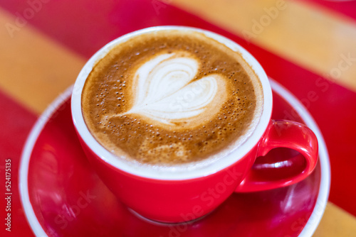 milk love heart on a flat white coffee in a red and white cup