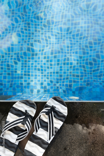top view swimming pool and pair of slippers vertical composition