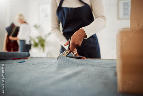 Fashion designer and tailor cutting fabric and making or preparing pattern for stylish, trendy and fashionable clothes. Workshop or boutique seamstress using denim material or textile for edgy wear