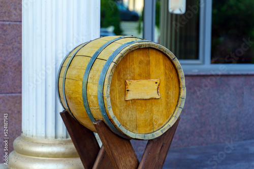 A wine barrel made of wood with a sign for the inscription stands on a special stand outside the building