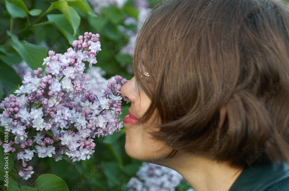 Naklejka premium Close up portrait of beautiful woman smelling purple lilac
