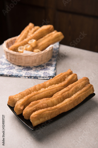 Cakwe or You tiao is a long golden-brown deep-fried strip of dough or typical chinese doughnut. Served in bamboo woven plate photo