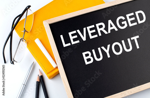 LEVERAGE BUYOUT text on blackboard with notepad , pen, pencil photo