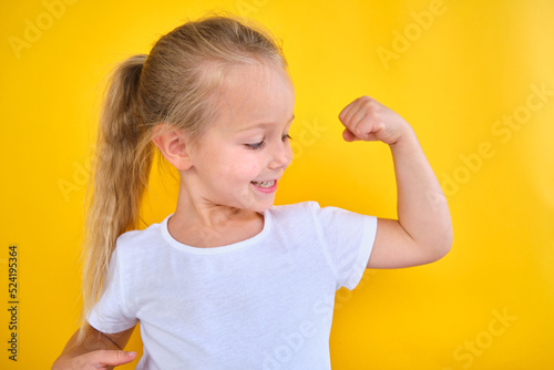 Schilderij op canvas portrait Strong preschool little girl showing flexing arm muscle smile isolated