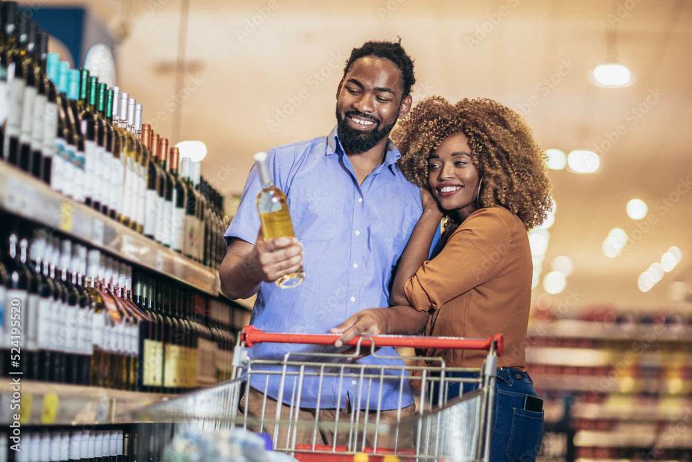 Smiling couple deciding what wine to buy in grocery store