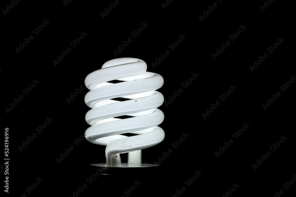 Glowing spiral light bulb isolated on dark background. Eco energy saving light bulb concept Glowing spiral light bulb isolated on dark background. Eco energy saving light bulb concept