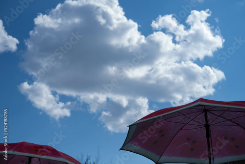 Beach umbrellas in row  with reflective highlights of water surface  with abstract pattern of light and shadow. Bottom up view of beach umbrellas against sky