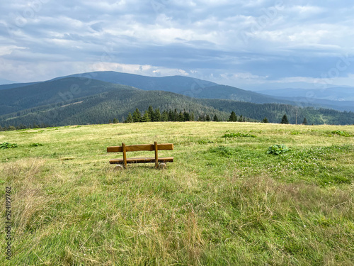 A bench in a meadow in front of the mountain shelter in Hala Rysianka in Beskid Zywiecki in Poland, where you can sit and admire the picturesque views of the surrounding areas