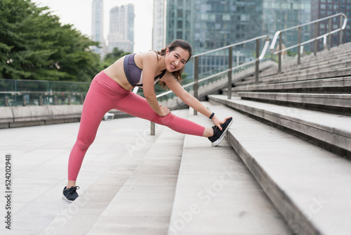 Young woman stretching in city street fitness leg press