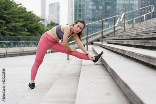 Young woman stretching in city street fitness leg press © Allen Chen