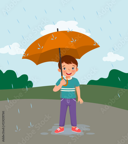 cute little boy holding umbrella in the rain on rainy day at the park