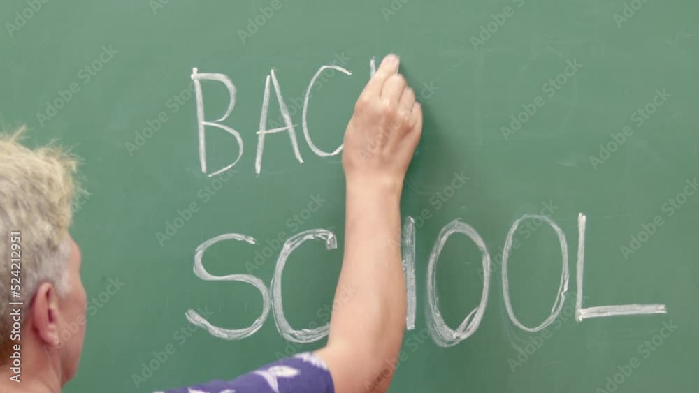 woman teacher student or girl hand is writing on blackboard with white chalk word back to school.senior gray hair woman back view.one hand raised up.education learning concept,autumn august september 