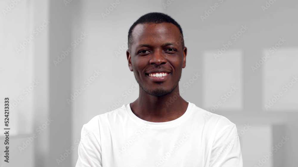 Portrait of African-American man look at camera and nod standing in white room Portrait of African-American man look at camera and nod standing in white room