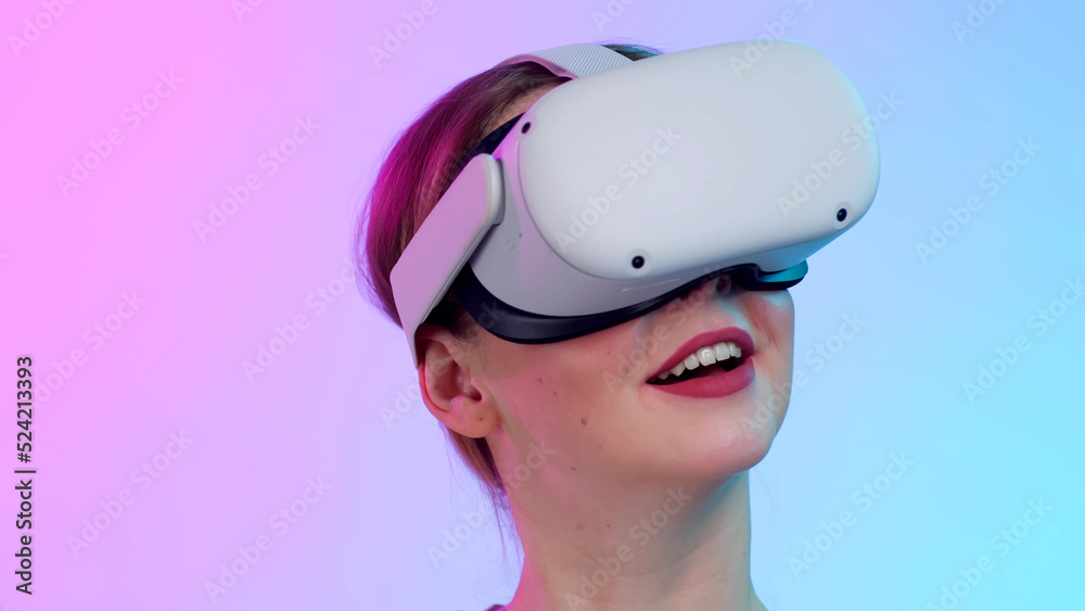 Closeup of young woman in vr glasses isolated over neon background Closeup of young woman in vr glasses isolated over neon background