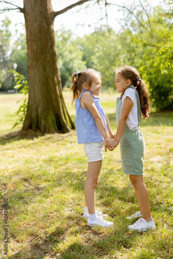 Fototapeta premium Two little girls holding hands in the park