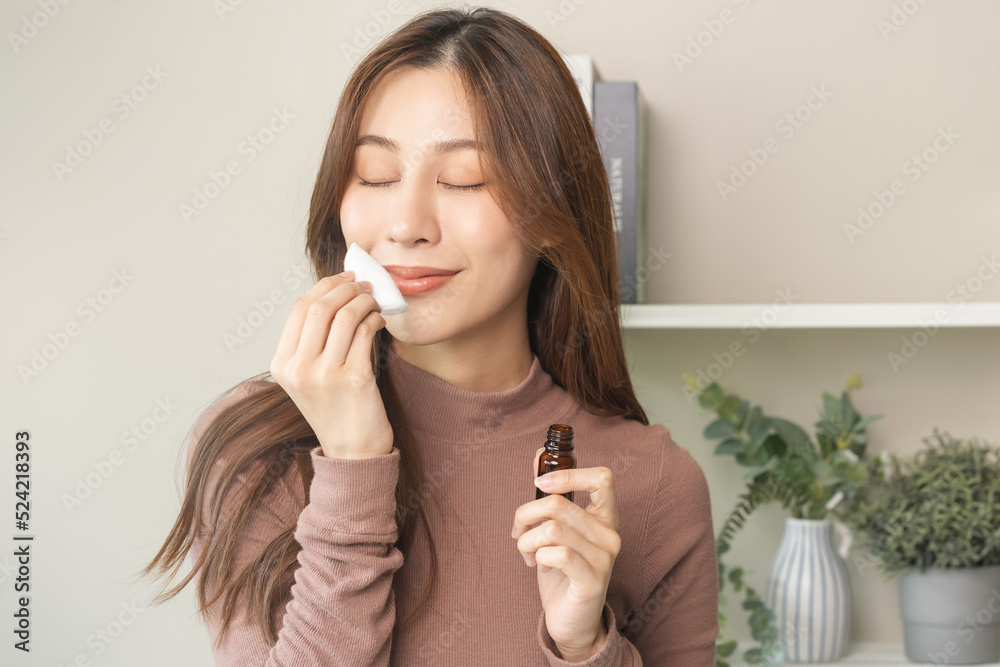 Aromatherapy, cute asian young woman holding cotton pad, bottle of essential perfume oil, enjoying smell fragrance of herbal from medicine natural organic at home. Therapy treatment, beauty skin care. Aromatherapy, cute asian young woman holding cotton pad, bottle of essential perfume oil, enjoying smell fragrance of herbal from medicine natural organic at home. Therapy treatment, beauty skin care.